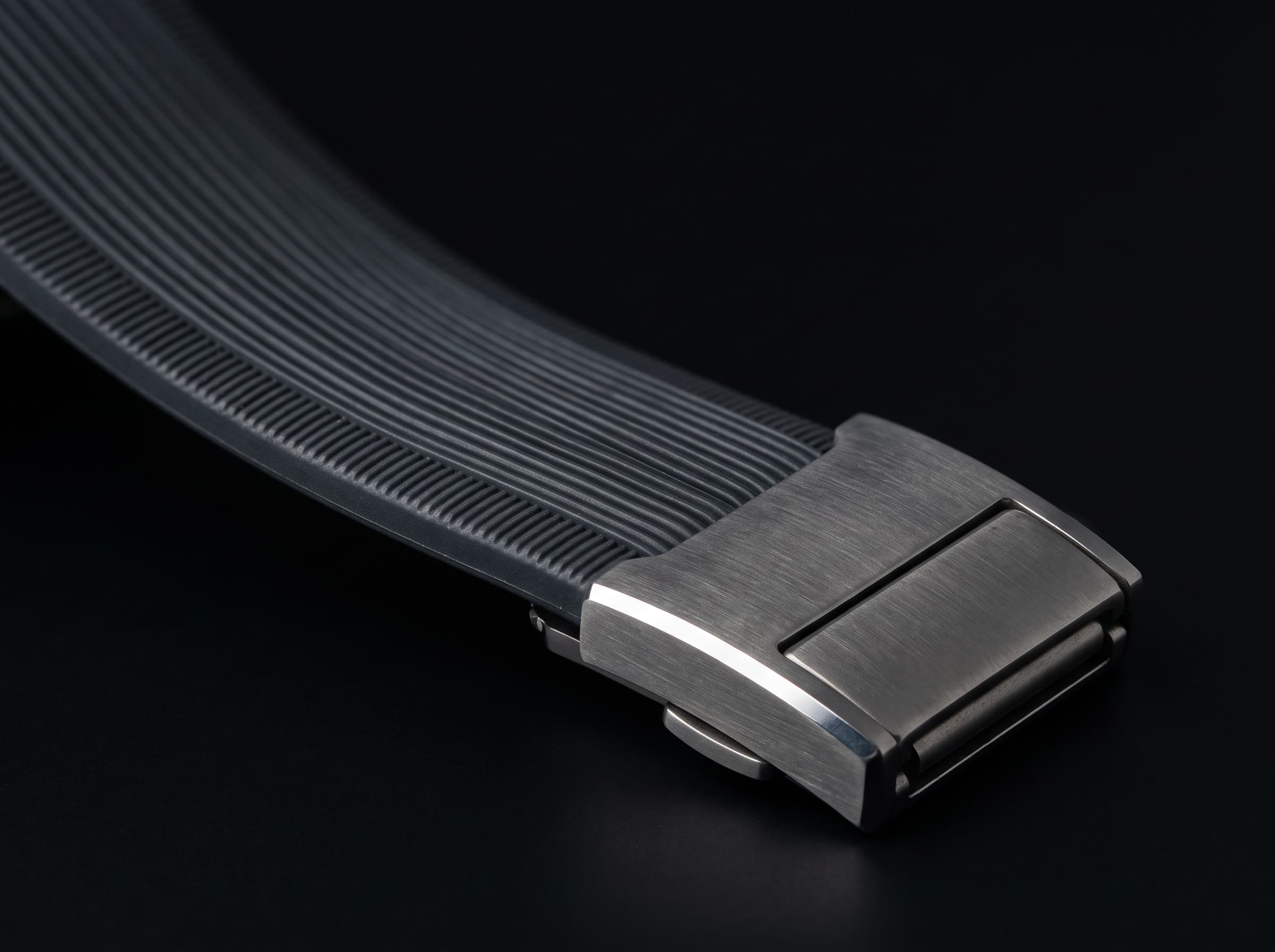 Ribbed charcoal band folding into a brushed titanium magnetic clasp