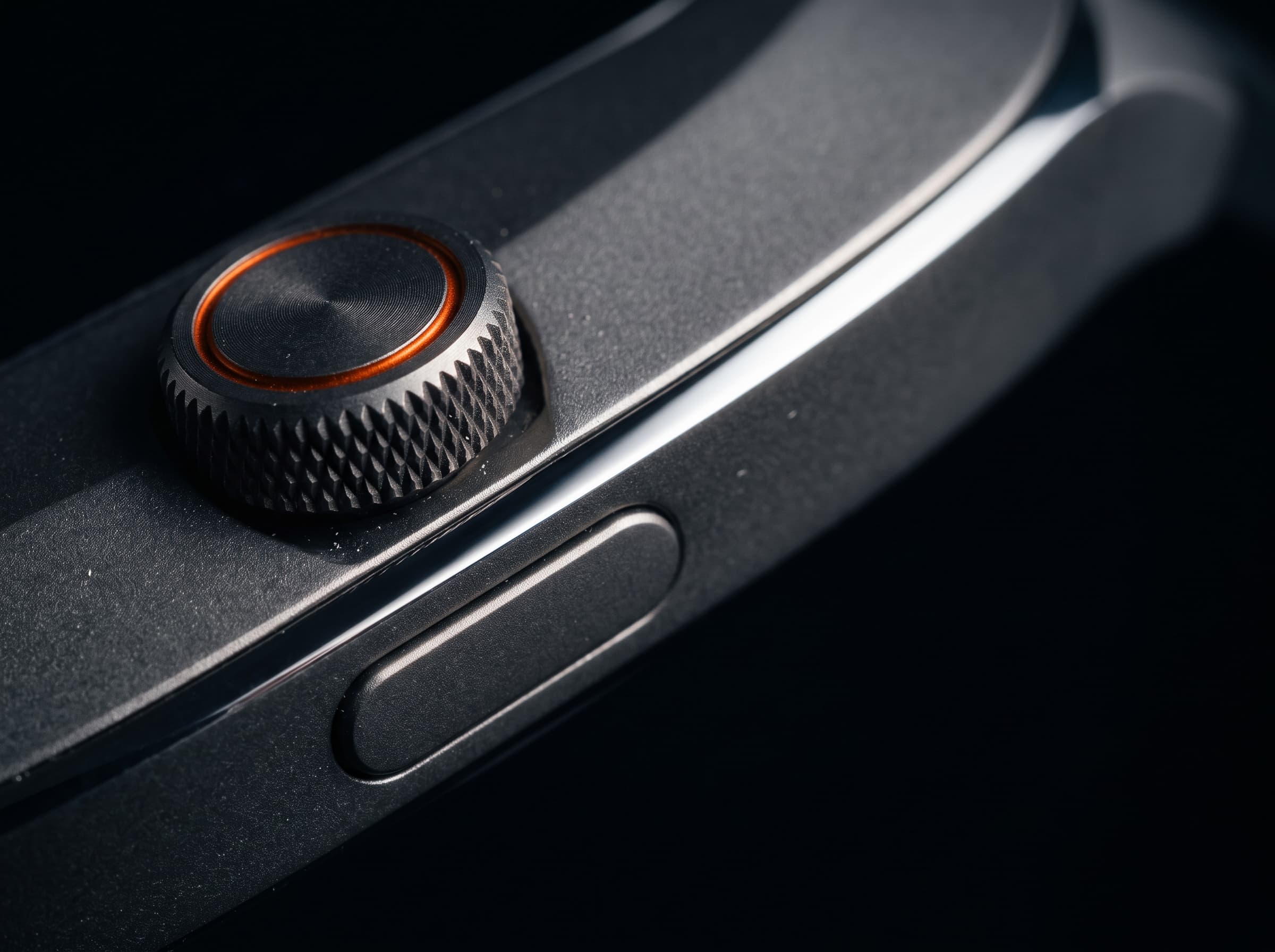 Macro of the knurled titanium crown with its ember ring, above the flush side button